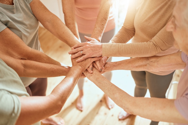 A group of adults form a hand-stack to represent teamwork and camaraderie.