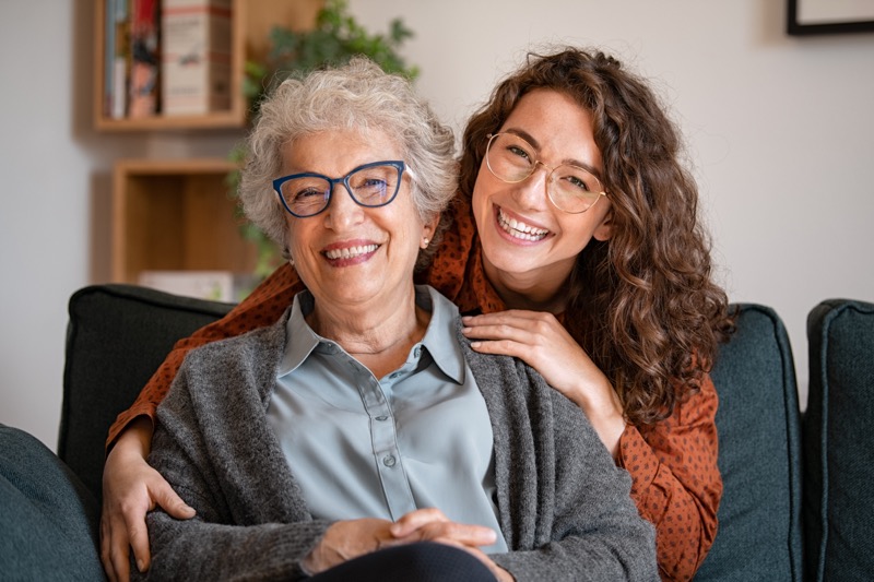 Happy grandmother with smiling granddaughter at home